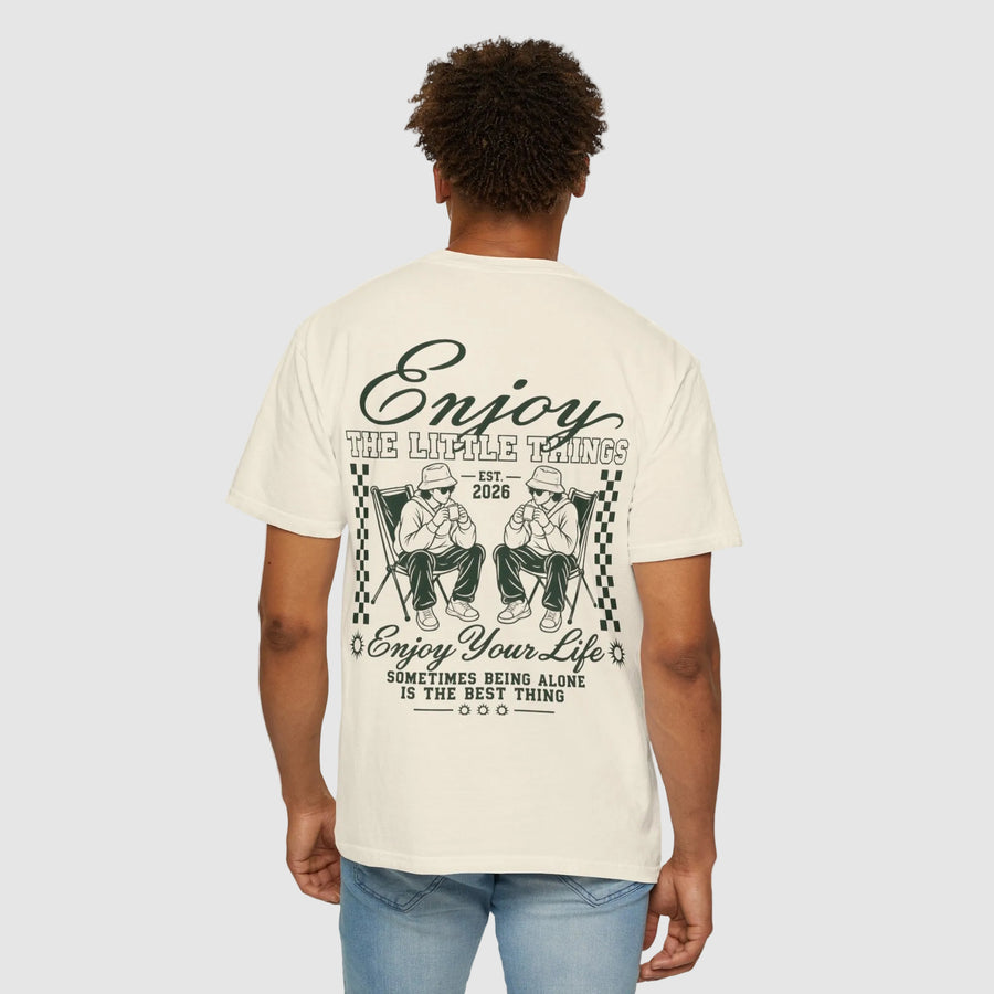 A man viewed from behind wearing a cream-colored t-shirt with a large black graphic print on the back featuring a skull and the text 'FOK AROUND FIND OUT', paired with blue jeans against a plain white background.