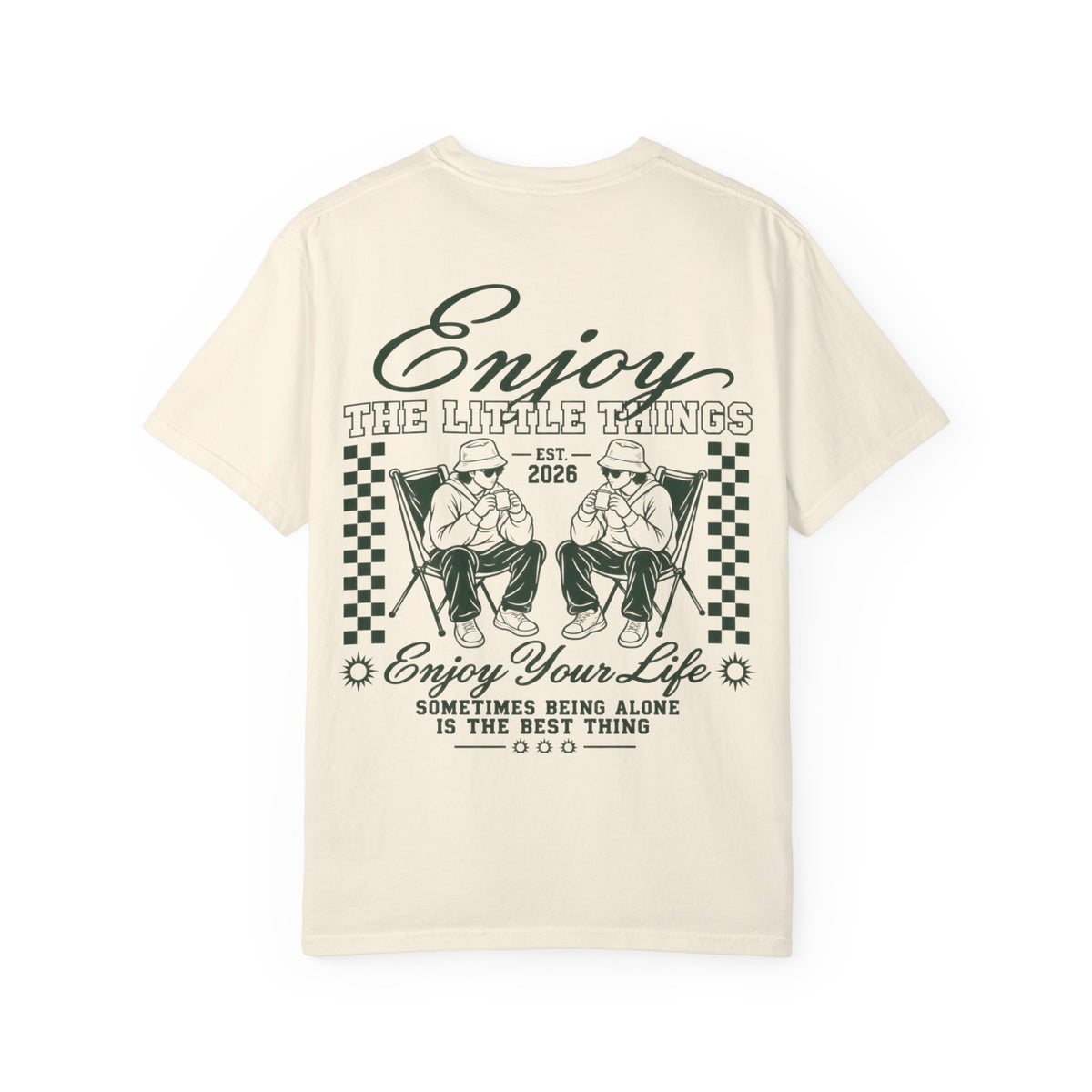 An off-white short-sleeve t-shirt with a dark green graphic print on the front. The graphic features the text 'Enjoy THE LITTLE THINGS' and 'Enjoy Your Life' along with an illustration of two children sitting in folding chairs.